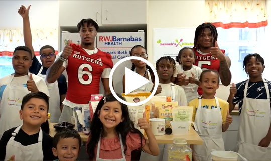 Rutgers Football Players Kaj Sanders and Shaquan Loyal in a group photo with the students at Hannah's Kitchen